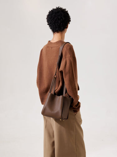 Medium Song Bag in chocolate pebbled leather with gold hardware, worn on shoulder by a person in brown sweater.