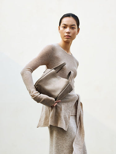 Medium Song Bag in Haze nubuck leather, with top handles and a structured design, held by a model.