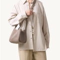 Medium Song Bag in Haze nubuck leather, worn by a person in a neutral outfit.