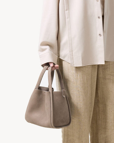 Medium Song Bag in Haze, matte-finish nubuck leather with O-shaped structure and magnetic closure.