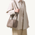 Medium Song Bag in Haze nubuck leather, worn on shoulder by a person in neutral-toned clothing.