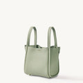 Medium Song Bag in jade green textured leather with dual top handles and subtle embossed logo.