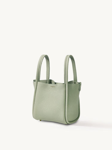Medium Song Bag in jade green textured leather with dual top handles and subtle embossed logo.