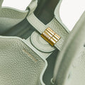 Medium Song Bag in Jade green pebbled leather with gold clasp detail and embossed logo.