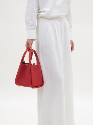 Medium Song Bag in Lucky Red pebbled leather with twin top handles and metallic base studs.