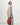Medium Song Bag in Poppy red nubuck leather, held by a woman in a tan knit outfit.
