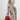 Medium Song Bag in poppy red nubuck, structured tote with dual handles and gold feet, worn with neutral knit.