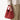 Medium Song Bag in vibrant Poppy red nubuck leather with a unique O-shaped structure and twin top handles.