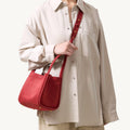 Medium Song Bag in Poppy red leather, featuring textured finish and gold hardware, worn by a model.