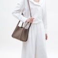 Medium Song Bag in taupe full-grain leather with adjustable strap. Elegant leather bucket bag for women.