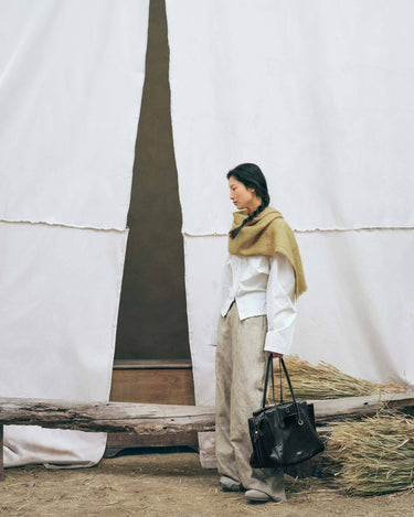 Onyx Medium Yore Duffle Bag: black leather tote with white stitching and gold hardware.