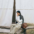 Medium Yore Duffle Bag in Sandal color, made of vegetable-tanned leather, with embossed pattern. Shown with a woman model.