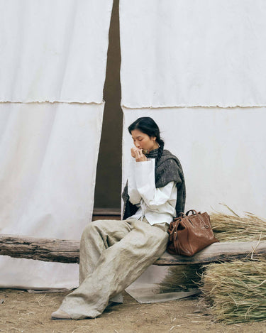 Medium Yore Duffle Bag in Sandal color, made of vegetable-tanned leather, with embossed pattern. Shown with a woman model.