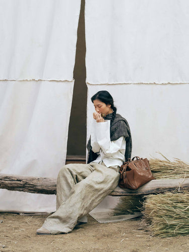 Medium Yore Duffle Bag in Sandal color, made of vegetable-tanned leather, with embossed pattern. Shown with a woman model.