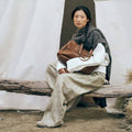 Medium Yore Duffle Bag in Sandal. Vegetable-tanned leather, timeless design, held by woman.