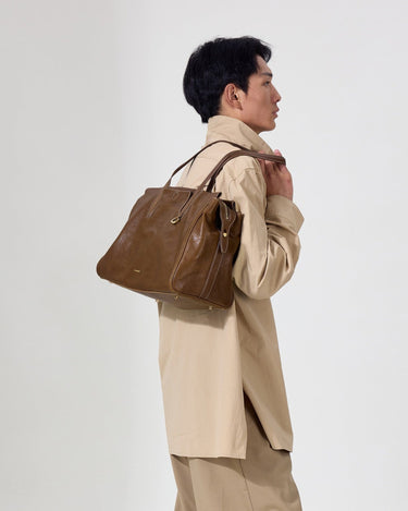 Medium Yore Duffle Bag in Sandal color, made of vegetable-tanned leather, worn by a man.