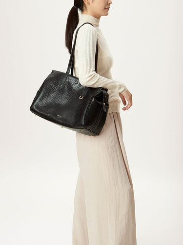 Medium Yore Duffle Bag in Onyx vegan leather worn by a woman. Features textured finish and gold hardware.