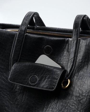 Medium Yore Duffle Bag in Onyx vegan leather, featuring a phone pocket and gold hardware.