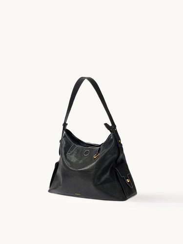 Medium Yore Hobo Bag in Onyx leather, featuring white stitching, adjustable strap, and exterior pockets.