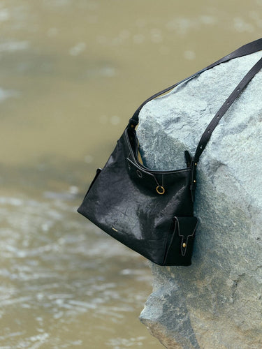 Medium Yore Hobo Bag in Onyx: Vegetable-tanned leather hobo bag with white stitching and adjustable strap.
