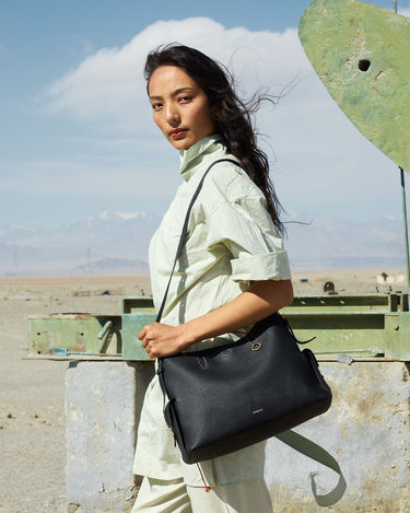 Medium Yore Hobo Bag in Onyx Grain full-grain leather, worn by a woman in a light green shirt.