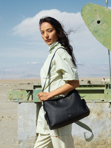 Medium Yore Hobo Bag in Onyx Grain full-grain leather, worn by a woman in a light green shirt.