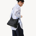 Medium Yore Hobo Bag in Onyx Grain leather worn by a model.