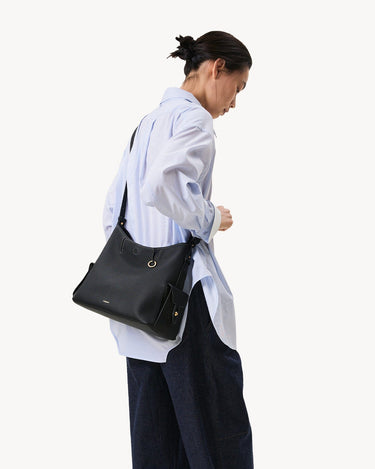 Medium Yore Hobo Bag in Onyx Grain leather worn by a model.