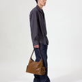 Medium Yore Hobo Bag, Sandal. Vegetable-tanned leather hobo bag with external pockets, worn by a model.
