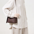 Burgundy Mini Drippy Roof Bag made of full-grain leather with gold hardware and white stitching, worn by a person.