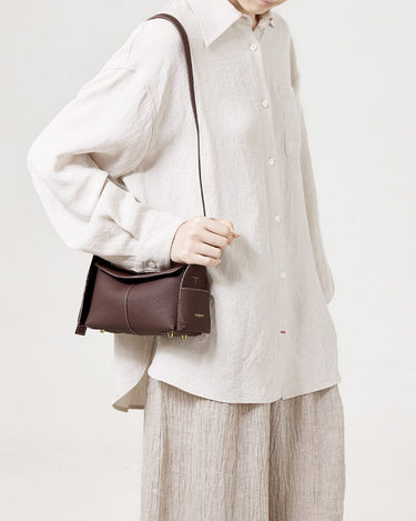Burgundy Mini Drippy Roof Bag made of full-grain leather with gold hardware and white stitching, worn by a person.