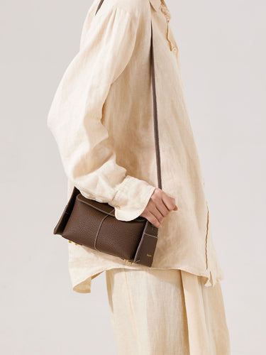 Brown Mini Drippy Roof Bag in textured leather with white stitching, worn by a person in a cream linen outfit.