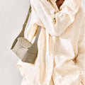 Mini Drippy Roof Bag in Cobble textured leather with adjustable strap, worn by a model in a cream linen shirt.