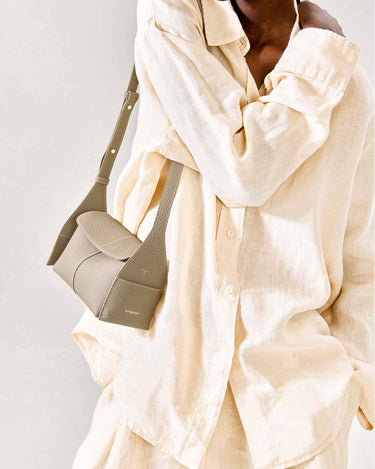 Mini Drippy Roof Bag in Cobble textured leather with adjustable strap, worn by a model in a cream linen shirt.