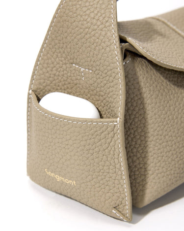 Mini Drippy Roof Bag in Cobble: Textured leather, gold 'Songmont' logo, and exterior pocket holding earbuds.