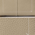 Close-up of textured taupe full-grain leather with white stitching detail on the Mini Drippy Roof Bag.