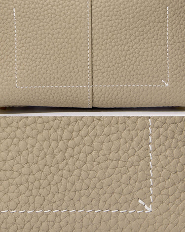 Close-up of textured taupe full-grain leather with white stitching detail on the Mini Drippy Roof Bag.
