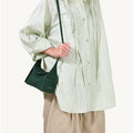 Emerald green Mini Drippy Roof Bag made of textured leather with a top handle, worn by a model.