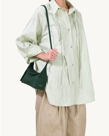 Emerald green Mini Drippy Roof Bag made of textured leather with a top handle, worn by a model.