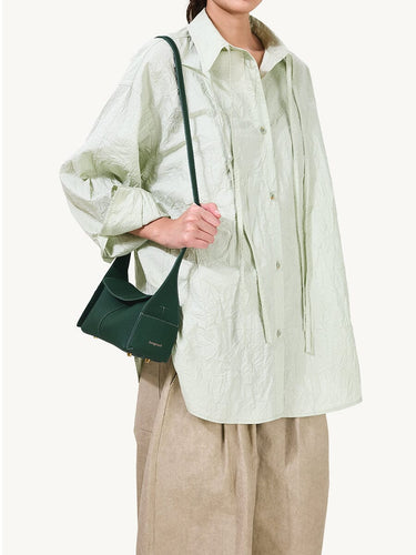 Emerald green Mini Drippy Roof Bag made of textured leather with a top handle, worn by a model.