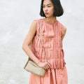Model wearing peach outfit with ivory Mini Drippy Roof Bag. Textured leather crossbody bag.