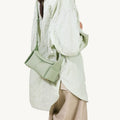 Sage green full-grain leather Mini Drippy Roof Bag with adjustable strap worn by a model.