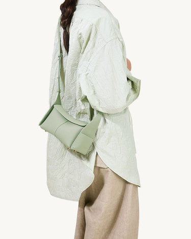 Sage green full-grain leather Mini Drippy Roof Bag with adjustable strap worn by a model.