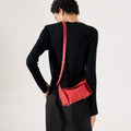 Red full-grain leather mini drippy roof bag with white stitching and gold hardware, worn by a woman.