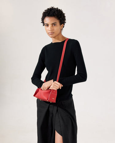 Red full-grain leather Mini Drippy Roof Bag with white stitching and gold hardware, worn by a model.
