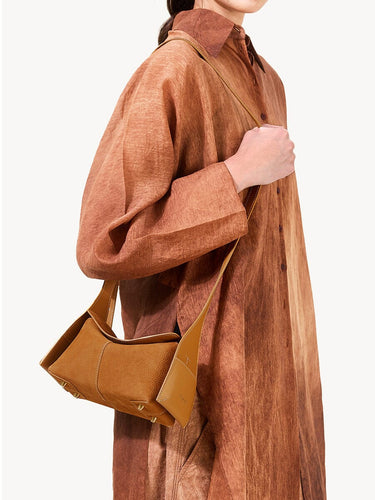 Mini Drippy Roof Bag in Sea Buckthorn nubuck leather with contrasting smooth leather details and visible stitching, worn by a woman in a brown dress.