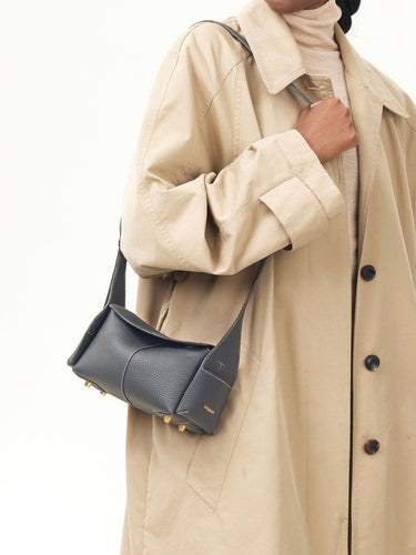 Mini Drippy Roof Bag in dark grey pebbled leather with white stitching and gold hardware, worn with a trench coat.