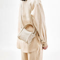 Ivory pebbled leather Mini Song Bag worn by a model in beige linen outfit