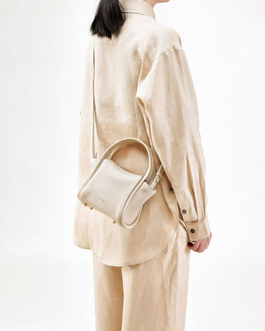 Ivory pebbled leather Mini Song Bag worn by a model in beige linen outfit