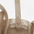 Ivory leather Mini Song Bag interior detail with gold stud closure and textured full-grain leather.